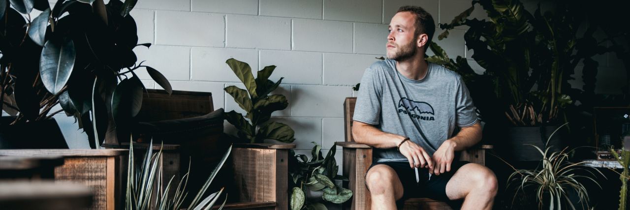 My ‘Pure O’ OCD Makes Me Obsessed With Every Outcome photo of man sitting around plants looking concerned or thoughtful