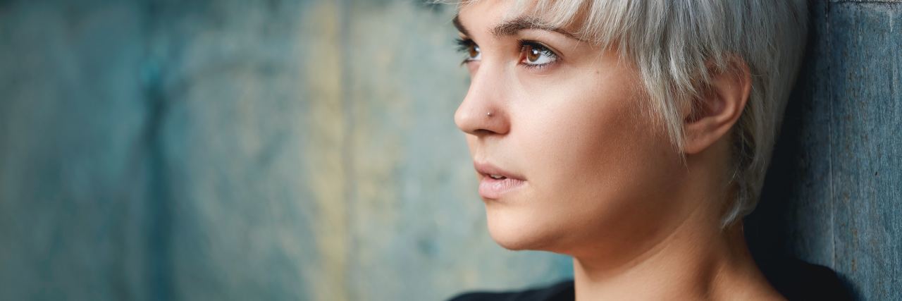 photo of woman with short light hair leaning against wall