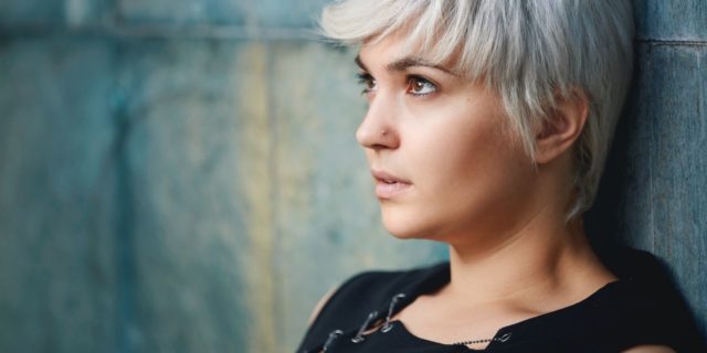 photo of woman with short light hair leaning against wall