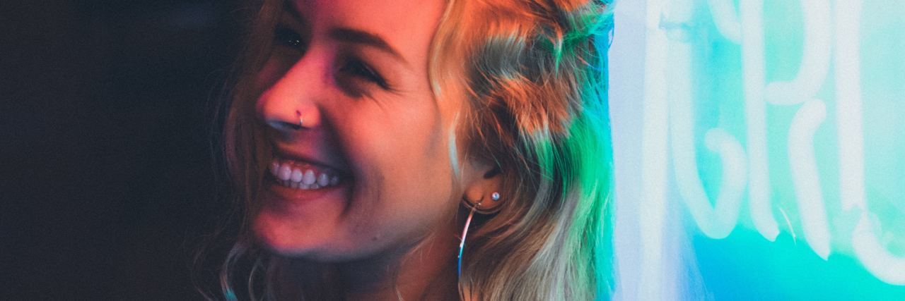 Struggling to Get Through Today With Depression photo of woman with blonde hair leaning against neon sign and smiling