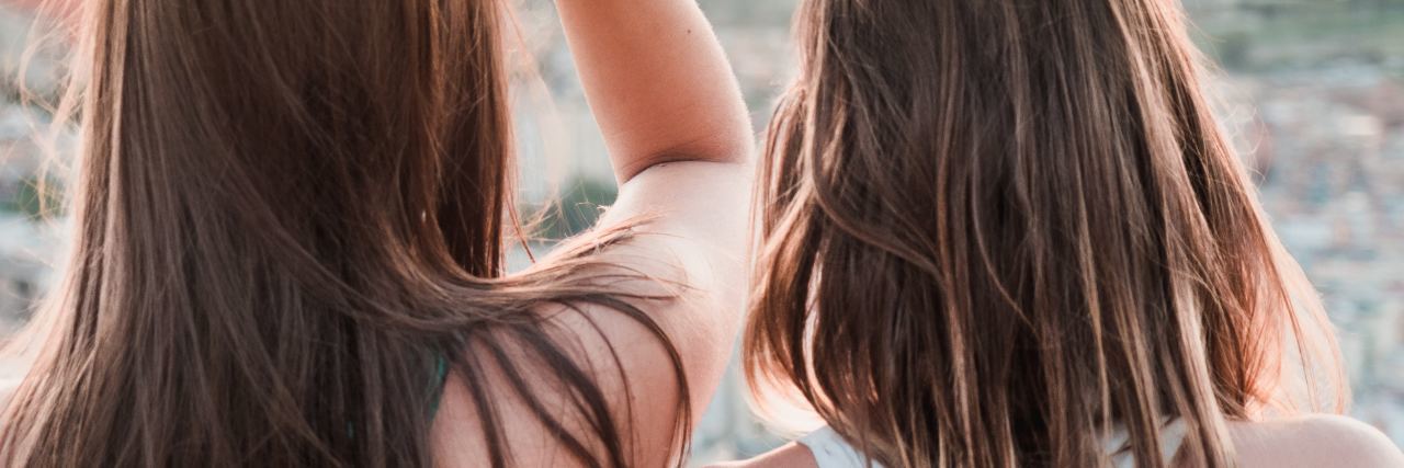 My Eating Disorder Journey Led Me to Help From My Best Friend photo of two young women looking out over city with sun setting behind hills