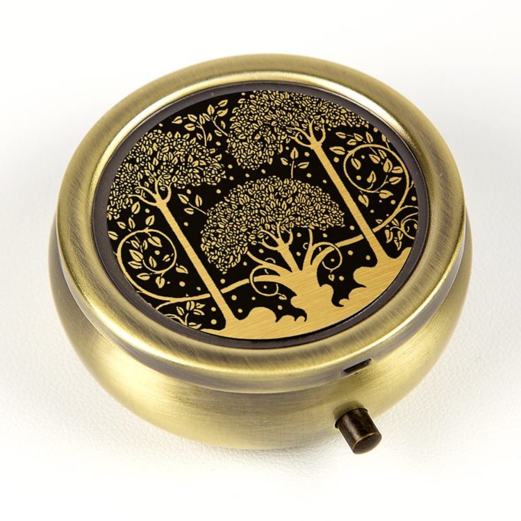 A pill box with golden trees on it, against a black background.