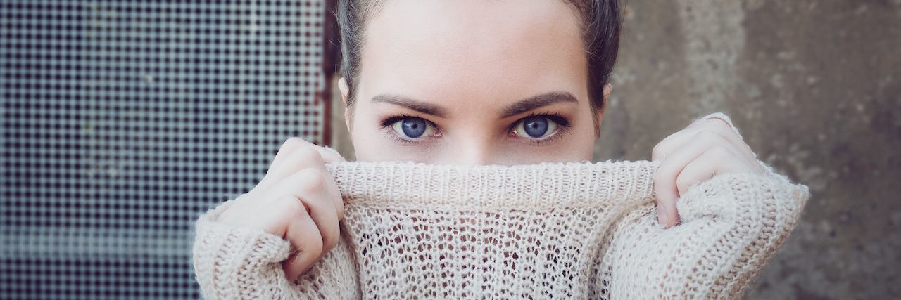 A woman pulling a sweatshirt over her face