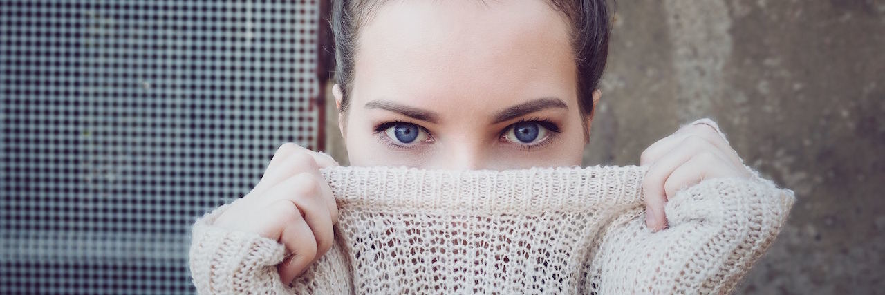 A woman pulling her sweater over her face