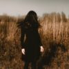 photo of woman standing in field with hair hiding face