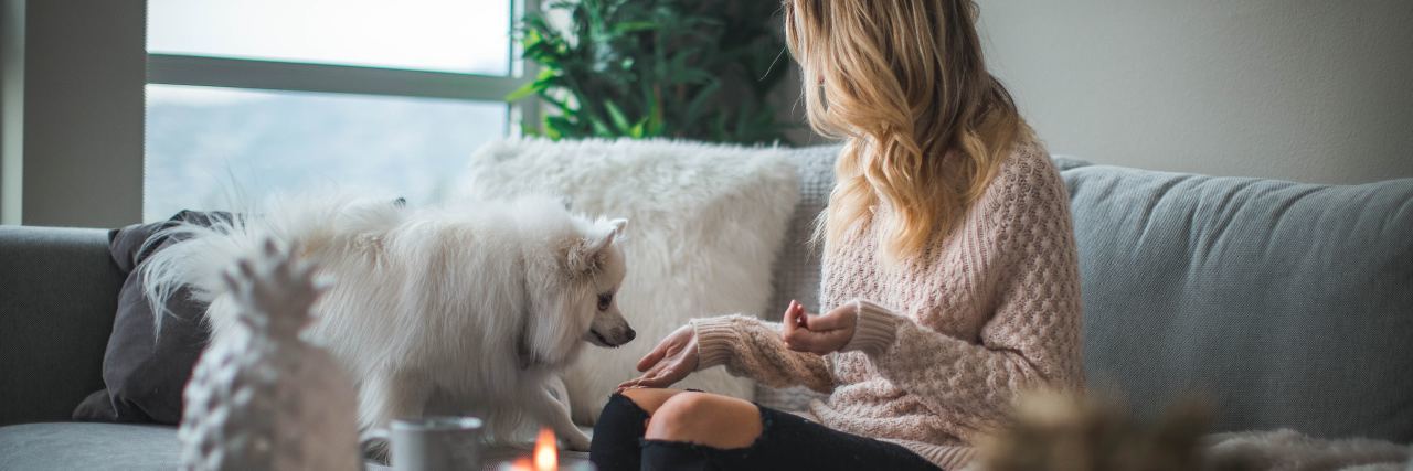 photo of woman relaxing at home with candles and white haired dog