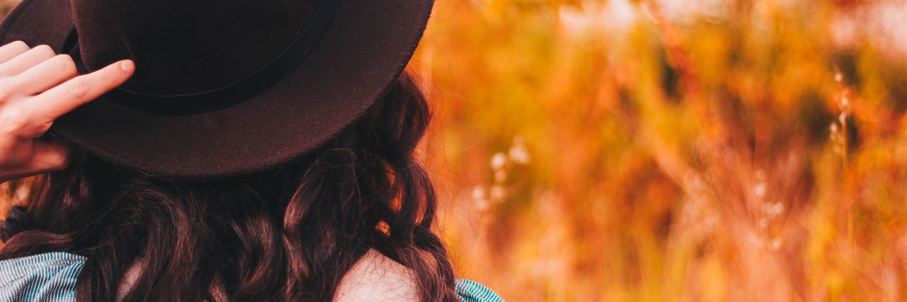 How to Start Mindfulness Without Meditation photo of woman wearing hat over long brown hair standing in front of orange grass or wheat