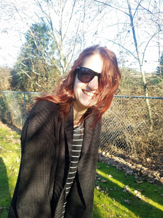 A photo of a young woman smiling into the camera, wearing sunglasses.