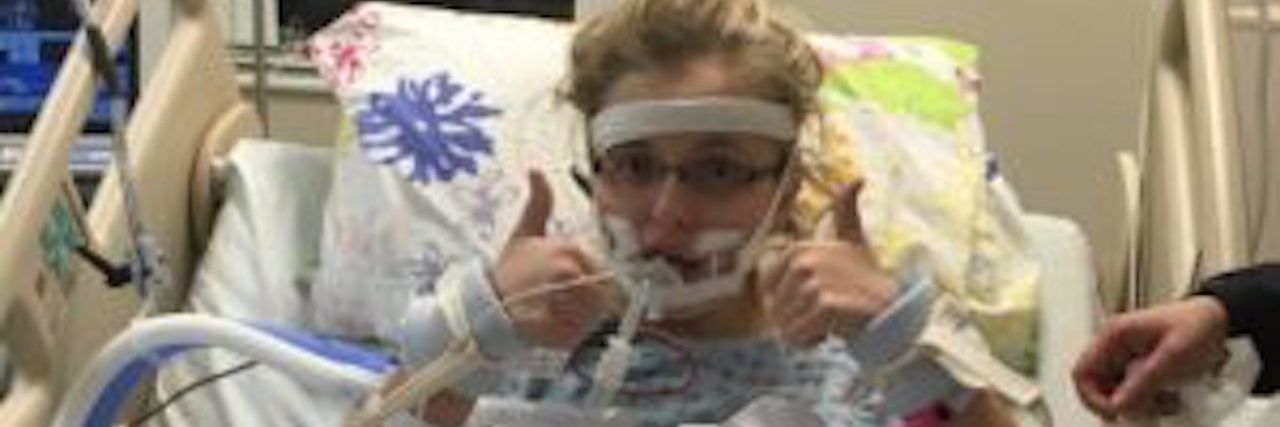 Receiving a Pediatric Stiff-Person Syndrome Diagnosis: What to Know The author in a hospital bed with her thumbs up