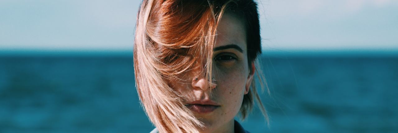 What I Wish People Knew About Eating Disorder Recovery White woman facing the camera with hair blowing in her face in front of the ocean