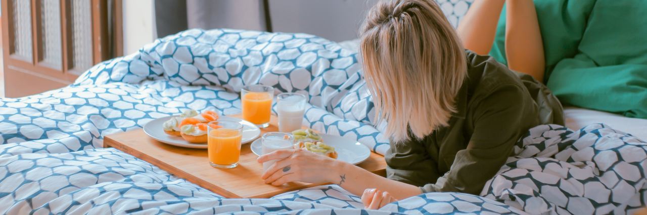 photo of woman lying on bed with healthy breakfast