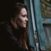 profile photo of woman looking out of window in dark house and smiling