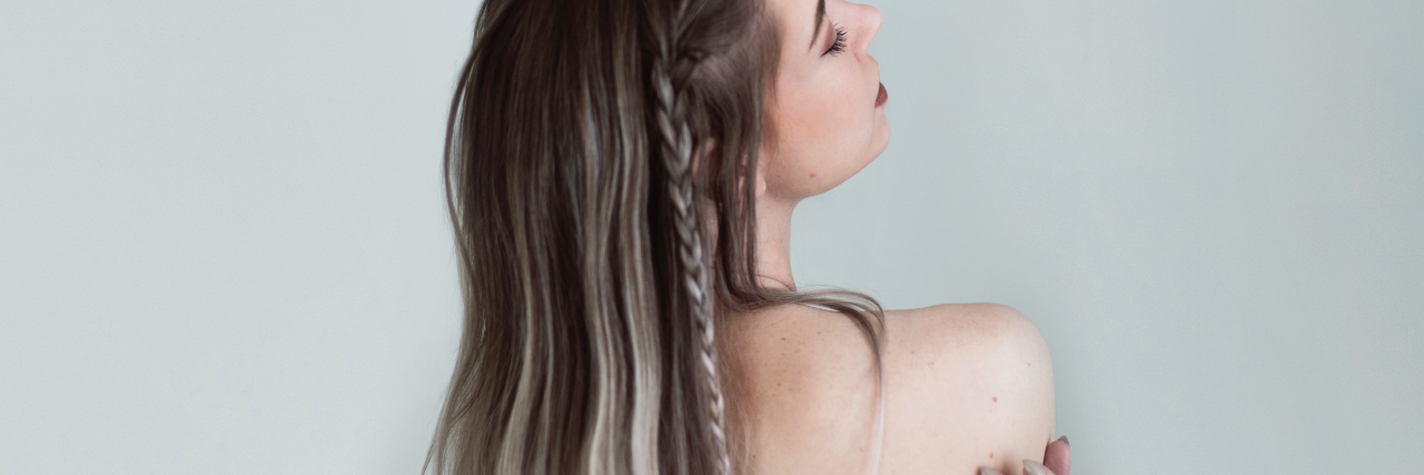 Why I Am Not 'Fighting' My Chronic Illness nude photo of woman facing away from camera with her arms wrapped around herself
