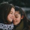 photo of two young women embracing in winter with smiles