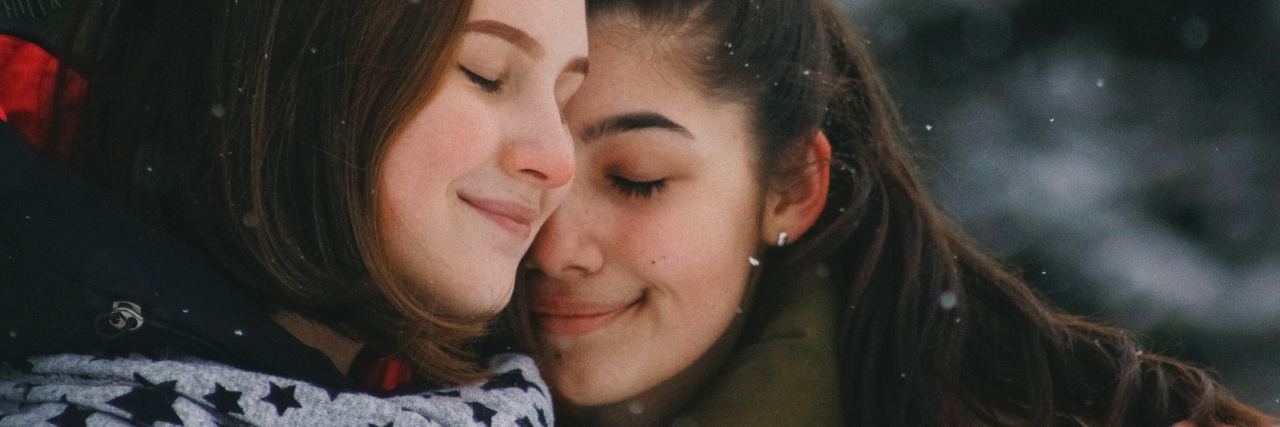 photo of two young women embracing in winter with smiles