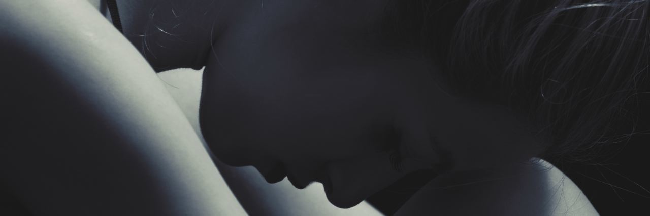 Why Eating Disorder Treatment Is Failing Patients in the UK close up black and white photo of woman hugging legs and resting head on knees