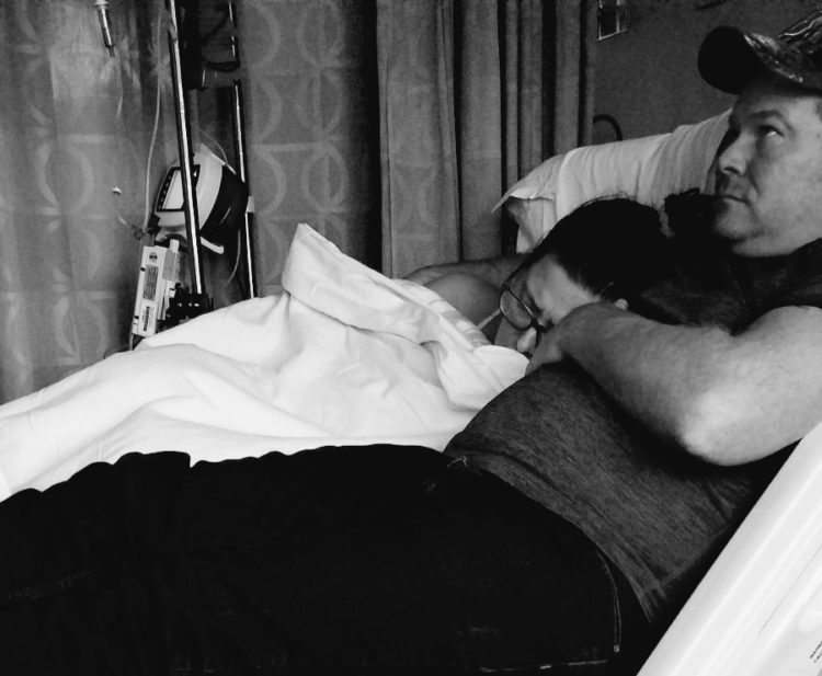 The author lying in a hospital bed with her husband