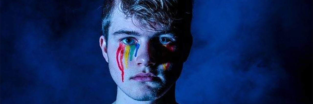 Man with rainbow makeup tears.