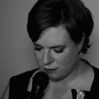 black and white close up photo of woman with closed eyes and microphone