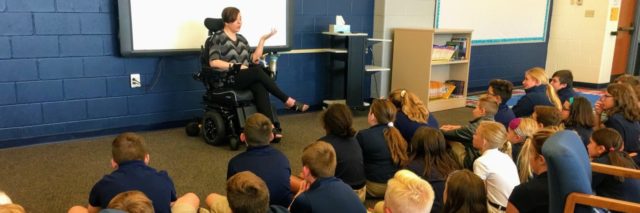 Marie in her wheelchair speaking to a group of sixth graders.