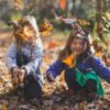 Two girls playing in autumn leaves.