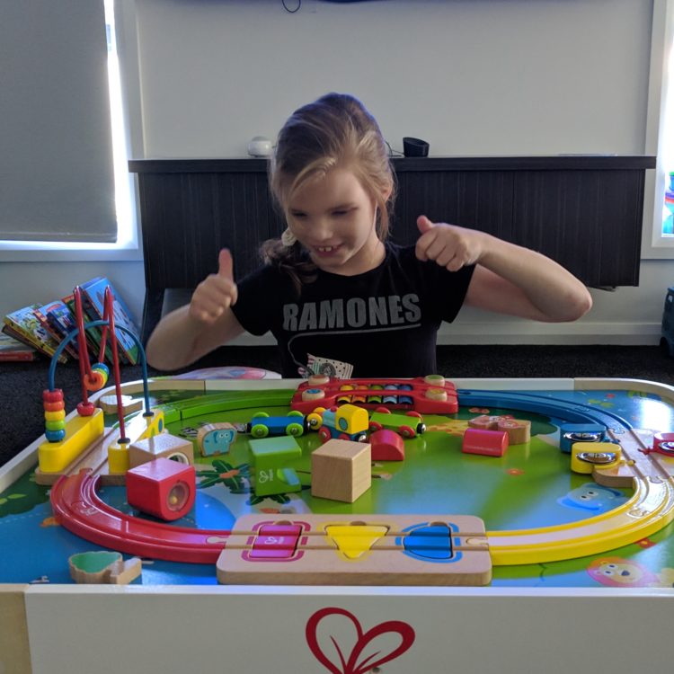 A little girl is giving a thumbs up while playing.