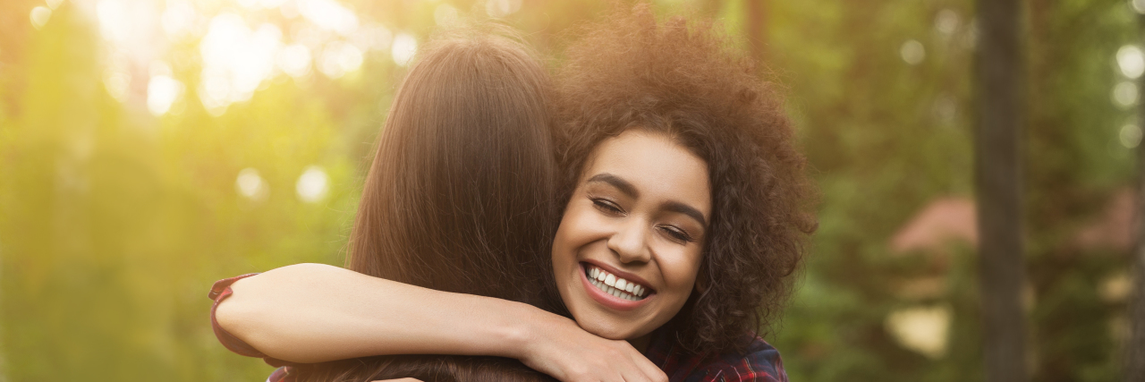 How to Support a Traumatic Brain Injury Survivor Two friends hug on a path in the park.