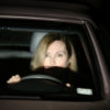a woman is in a car behind the wheel with headlights shining in her face