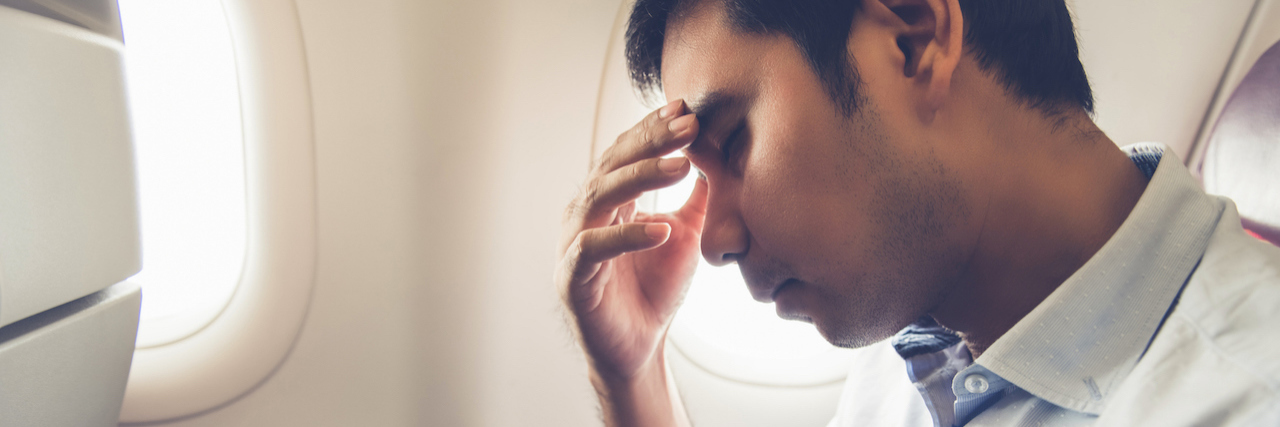 Flying Anxiety: What to Know About Plane Crashes A man sitting in an airplane, reading his head on his hands