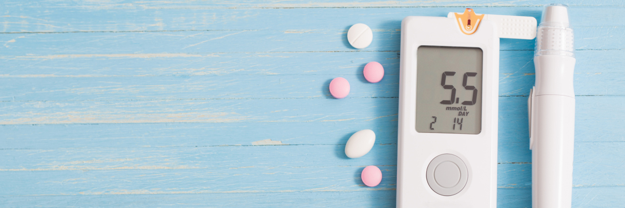 First Oral Drugs Developed to Treat Type 1 Diabetes Under Review glucometer and pills on blue wooden background