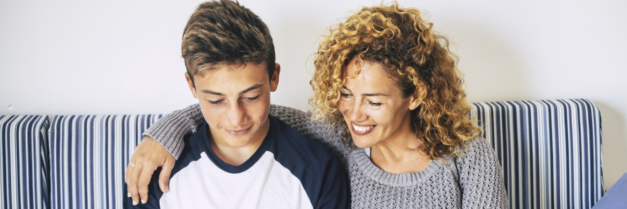 Dear Custodial And Local Non-Custodial Parent a mom and son sitting on couch smiling looking at a laptop