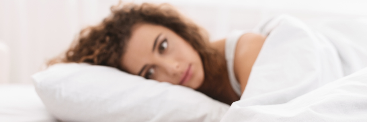 young woman looking at phone in bed