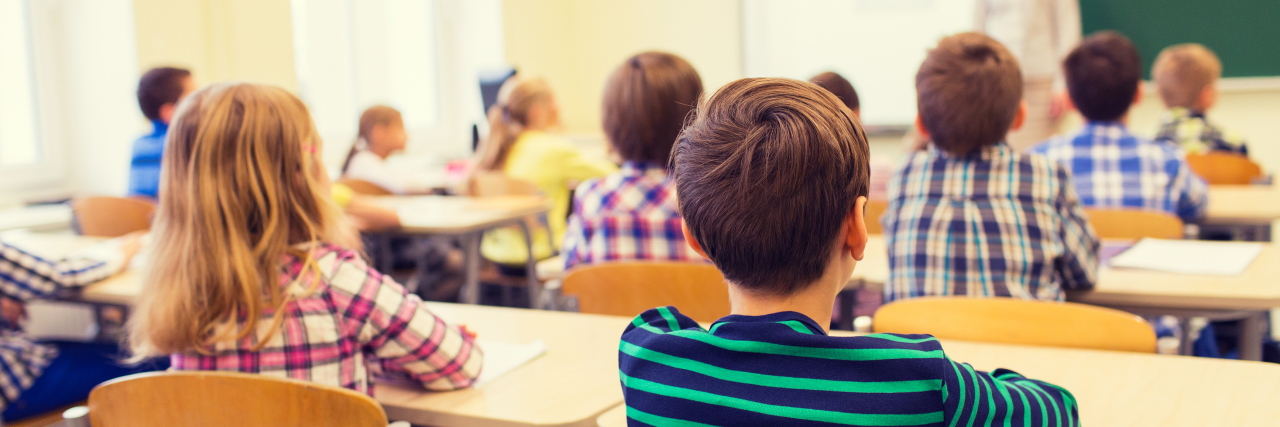 The Skill I Learned From the Kids Who Picked on Me Because I Stutter education, elementary school, learning and people concept - group of school kids sitting and listening to teacher in classroom from back
