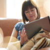 A woman on her couch, touching her ipad.