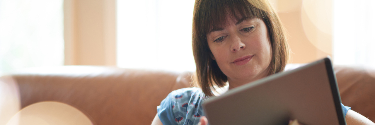 How Technology Has Improved My Life With Chronic Illness A woman on her couch, touching her ipad.