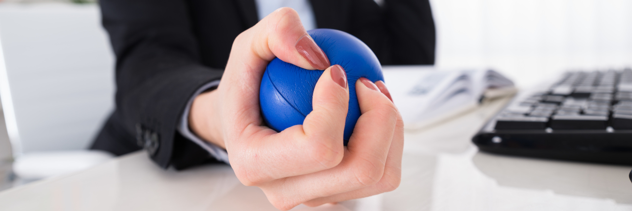 The Mental Health Benefits of Stimming for People With Autism Woman using a stress ball at work..