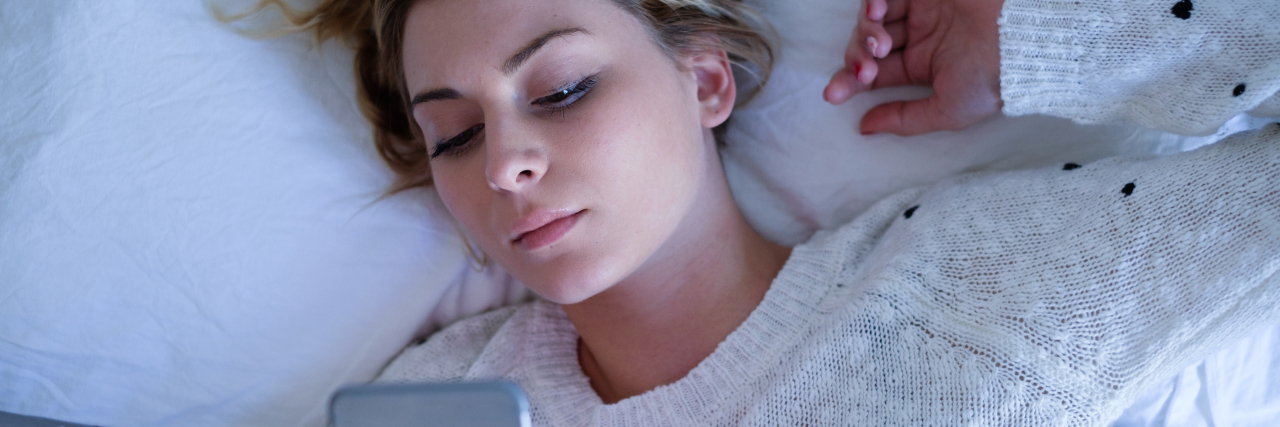 What It's Like Being Unreliable With Chronic Illness girl laying in bed on her cell phone