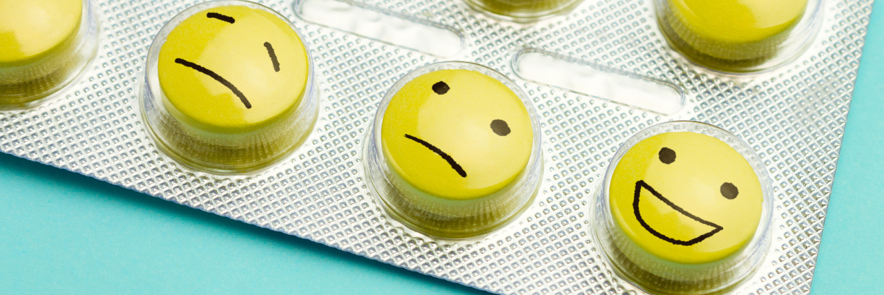 Researchers Argue for Longer Taper When Stopping Antidepressants Yellow pills with two sad faces and one happy face on a blue background