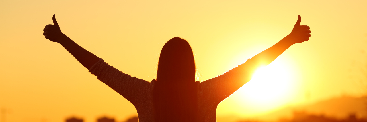 Celebrate Your Small Victories After Becoming Disabled Woman giving thumbs up at sunset.