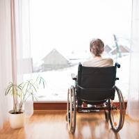 photo of woman from behind sitting in wheelchair looking out of window