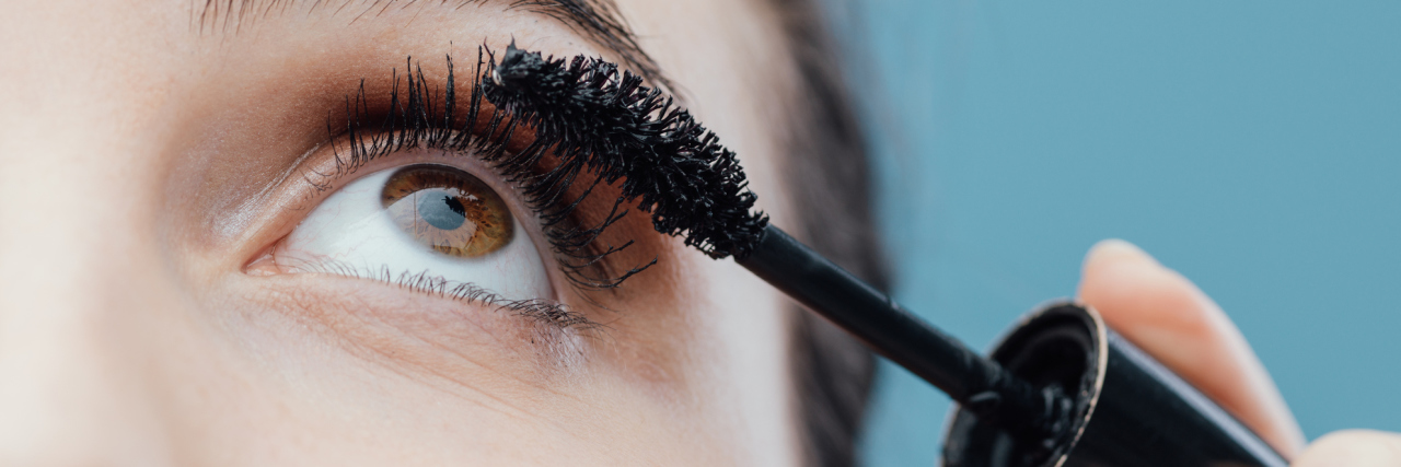 Woman applying mascara on her lashes