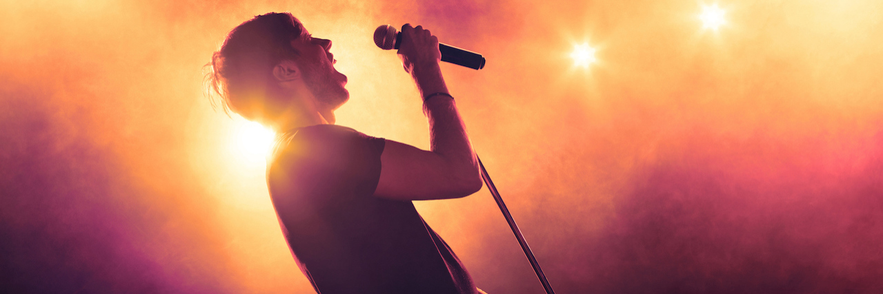 Borderline Personality Disorder: Obsession With Musicians A musician on state singing into a microphone surrounded by lights and fog