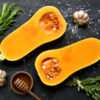 Halves of raw organic butternut squash with spices and ingredients for cooking.