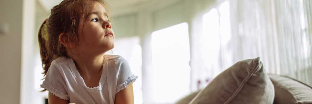 How to Heal If You Were Raised by an Abusive, Narcissistic Parent A young girl sitting on a couch, looking up.