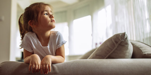 How to Heal If You Were Raised by an Abusive, Narcissistic Parent A young girl sitting on a couch, looking up.