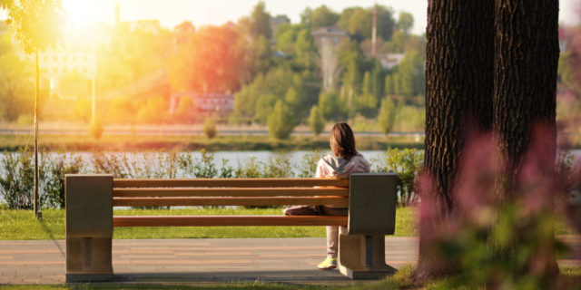 young woman sitting on bench near a lake