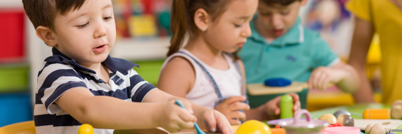 How Early Intervention Services Helped My Son With Autism Children playing with clay in classroom.