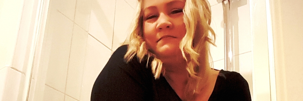 Feeling Ashamed to Need a Shower Stool With Chronic Illness photo of woman wearing clothes in shower posing on shower stool