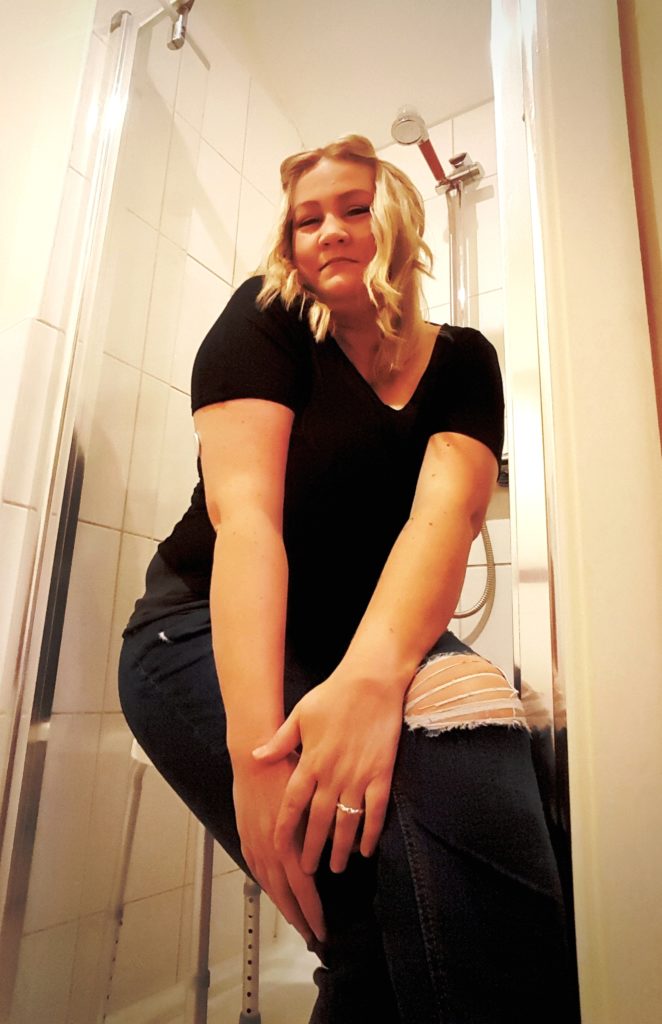 photo of woman wearing clothes in shower posing on shower stool