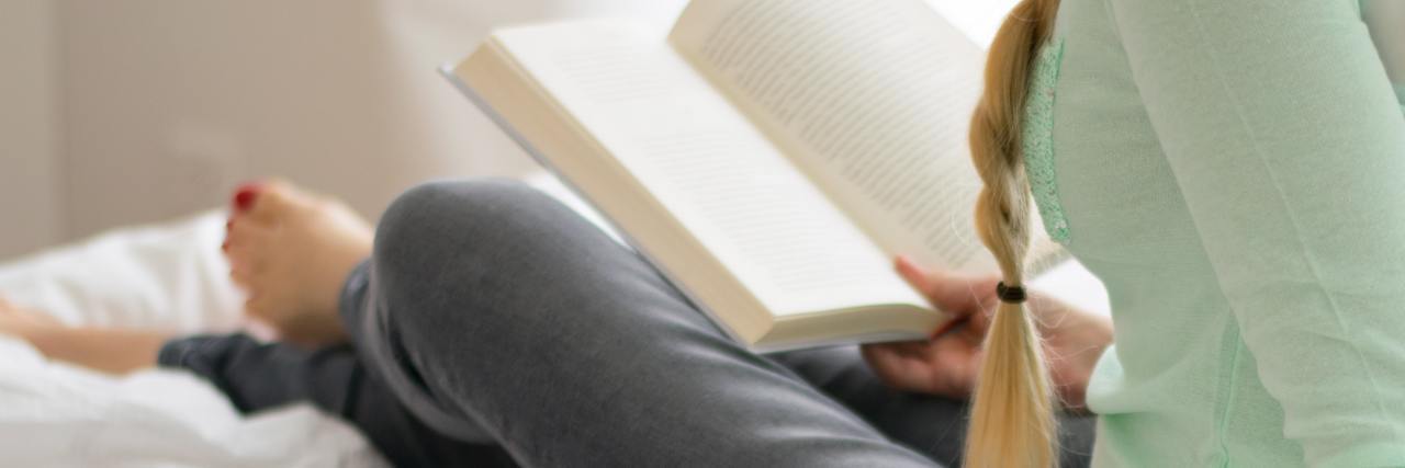 21 Cheap, Healthy Ways to Practice Self-Care woman reading a book on bed